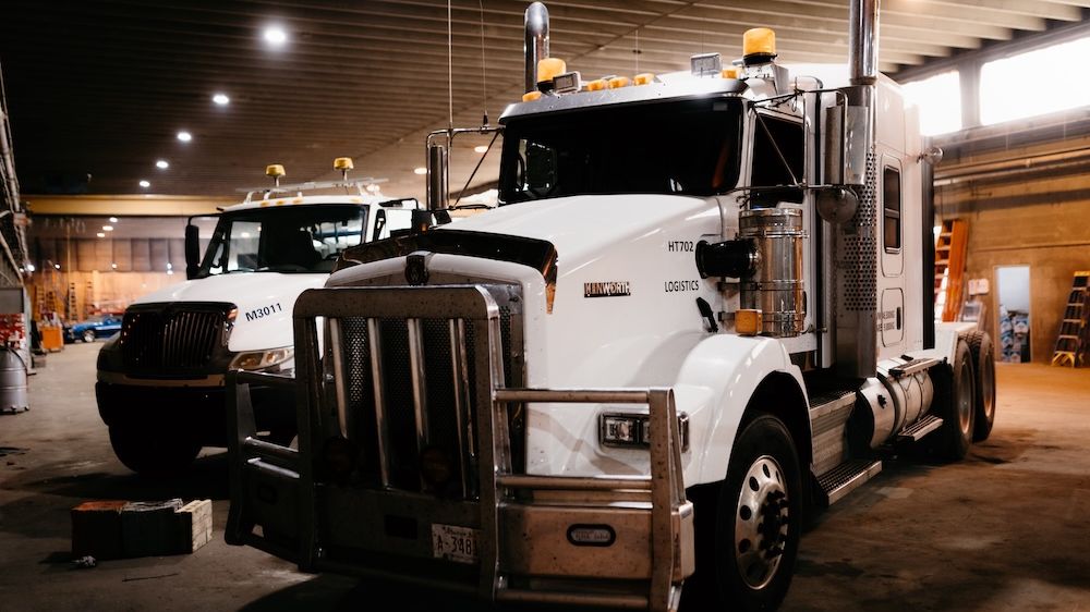 Two commercial highway trucks parked inside the Mach 6 service bay in Edmonton