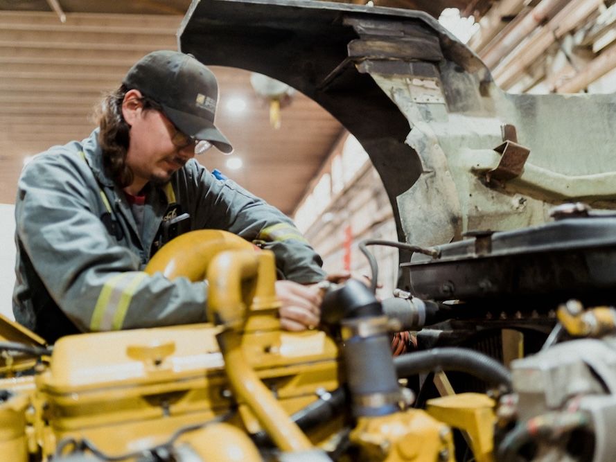 Mach 6 technician working inside an engine bay on heavy equipment